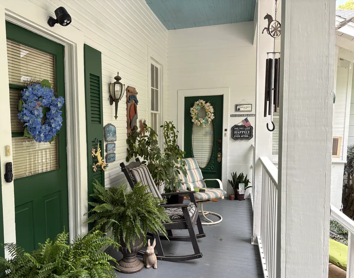 Front porch with white siding, deep green front doors and shutters, and a fresh grey painted deck floor.