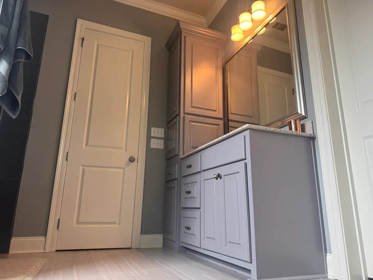 Wider view of the same bathroom showing the painted door, casings, and vanity cabinetry.